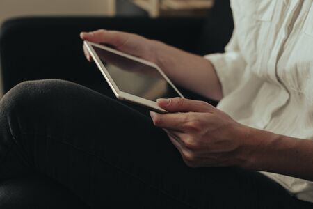 Mockup image of a woman sitting and holding white tablet pc with blank desktop screen 