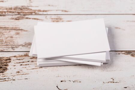 Mock up blank white business cards on light rustic natural wooden background.