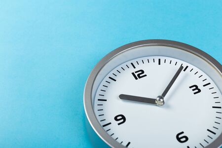 minimalistic white wall clock with light metal on a blue background. time concept.