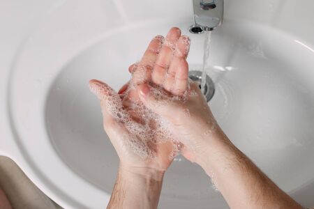 Hygiene concept. Washing hands with soap under the tap with water. handsome male hands and water in...