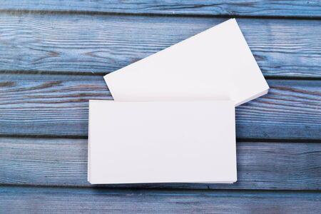 Close-up of mock up two empty stacks of business cards on a blue-violet natural wooden background.