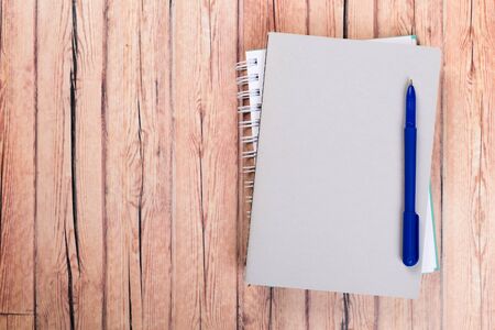Empty paper notebook on brown wooden table background. Top view Concept of a new workplace of office desks.の写真素材