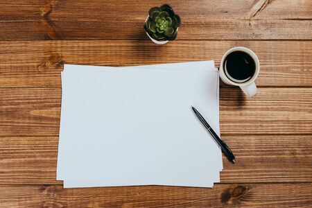 A4 blank paper, cup of coffee on wooden table background. Blank branding template.Photo blank form....