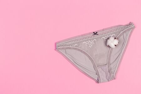 Female pastel cotton set panties and cotton flower on pink background top view flat lay with copy...