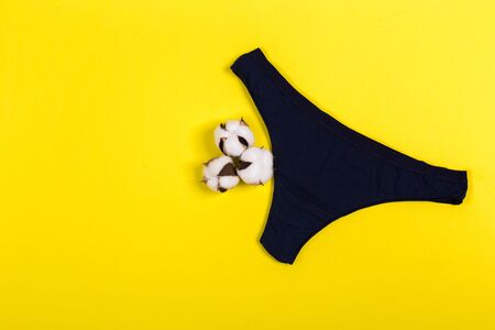 Female pastel cotton set panties and cotton flower on yellow background top view flat lay with copy space for text. Fashion blog, Colorful women's natural underwear, advertising, shopping concept.の写真素材