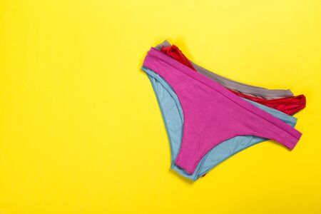 Female pastel cotton set panties and cotton flower on yellow background top view flat lay with copy space for text. Fashion blog, Colorful women's natural underwear, advertising, shopping concept.の写真素材