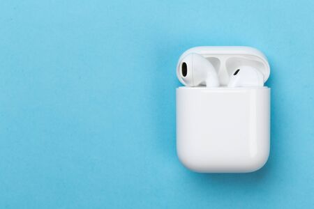 white wireless headphones with microphone on a blue background with charger