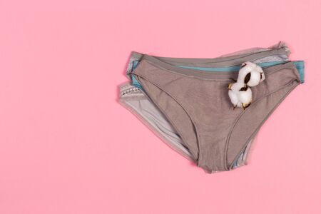 Female pastel cotton set panties and cotton flower on pink background top view flat lay with copy space for text. Fashion blog, Colorful women's natural underwear, advertising, shopping concept.の写真素材