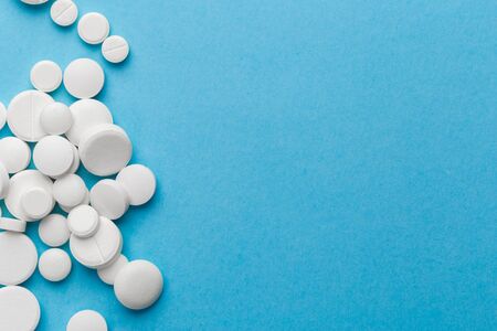 scattered white pills on a blue table. Layout for special offers such as advertising or other ideas....