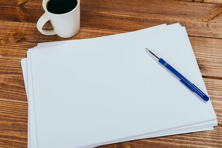 A4 blank paper, cup of coffee on wooden table background. Blank branding template.Photo blank form....