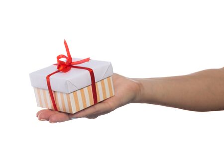 female hand holds a beautiful gift box with a bow isolated on white backgroundの写真素材