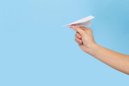 Hands holding the sign of paper airplane or message on blue studio background. Negative space,...