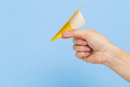 Hands holding the sign of paper airplane or message on blue studio background. Negative space,...