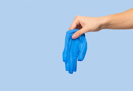 The doctor puts on sterile gloves on a blue background. Infection control concept. Danger