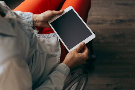 unrecognizable young disabled woman in a wheelchair with a modern tablet. Recovery and healthcare concepts.の写真素材