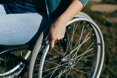 Unrecognizable disabled woman young woman in a wheelchair outdoors in a park. Recovery and healthcare concepts.の写真素材