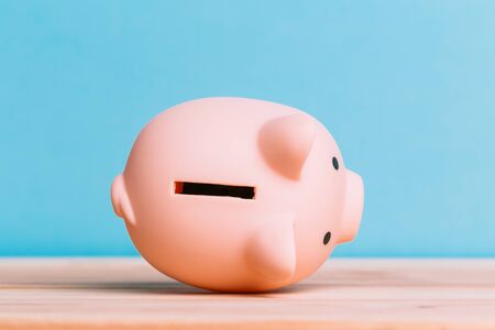 pink piggy bank on a wooden table and blue background. The concept of storage, accumulation and investmentの写真素材