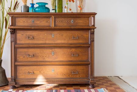 old antique old mahogany chest of drawers in a room with additional decorの写真素材