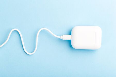 wireless headphones with charging case and wire on a blue background. The concept of modern technology, gadgets.の写真素材