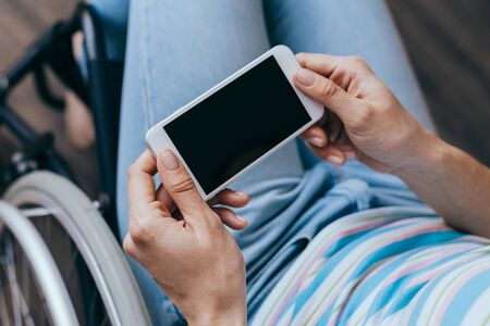 close up of a young woman in a wheelchair with a mobile phone in her hands at home.  healthcare concepts.の写真素材