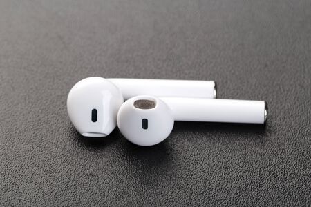 Modern wireless headphones on a dark black background. Modern technology concept