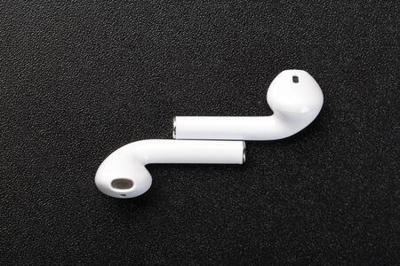 Modern wireless headphones on a dark black background. Modern technology concept