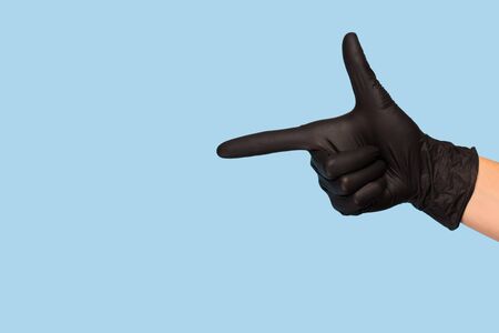 Woman's hand in a black medical glove points to an empty place on a blue background. the control. mock upの写真素材