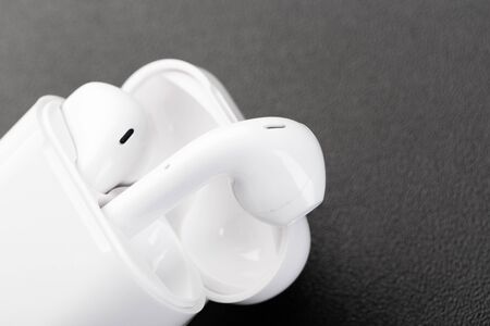 Modern wireless bluetooth headphones with charging case on a dark black background. The concept of...