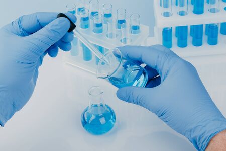 Laboratory glassware with test tubes. scientific laboratory equipment. hands of a scientific researcher in blue glovesの写真素材