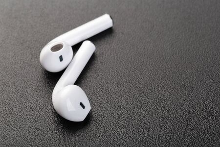 Modern wireless bluetooth headphones on a dark black background. Modern technology concept