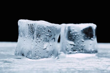 several melted ice cubes with drops on a dark black backgroundの写真素材