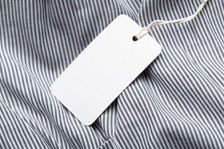 Clothing tag, label blank mockup on a clothes, to place your design.  fashion, people and shopping concept - close up price tag of clothing itemの写真素材