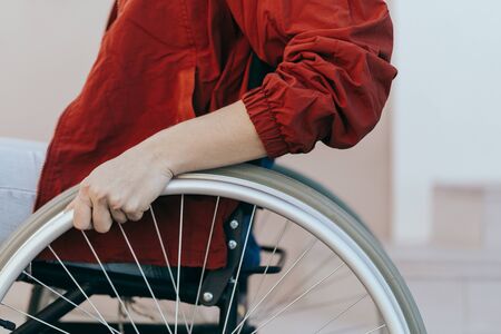 Unrecognizable disabled woman young woman in a wheelchair outdoors in a park. Recovery and healthcare concepts.の写真素材
