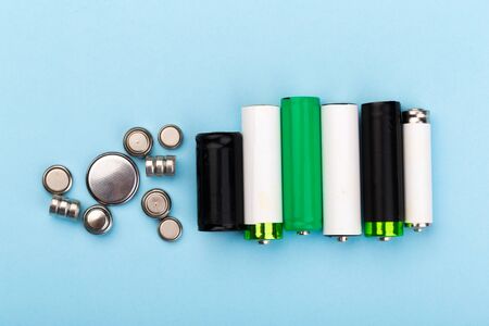 many new and used AA batteries on a blue background.