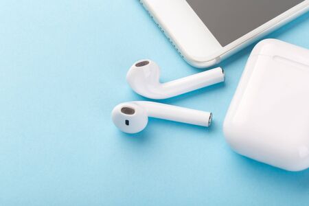 Wireless  headphones with a modern mobile phone on a blue background. The concept of modern...