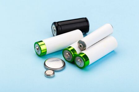 many new and used AA batteries on a blue background.