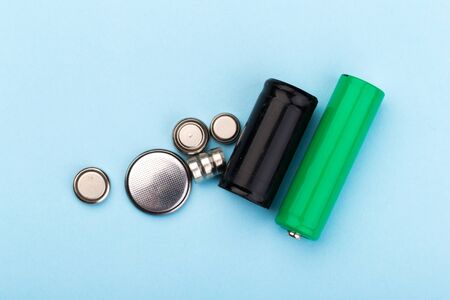 many new and used AA batteries on a blue background.