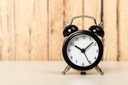 Black retro alarm clock with bells on a wooden table, daily routine concept. ten hours 10 minutesの写真素材