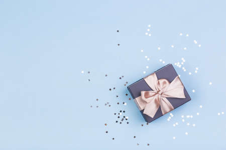 Gift or gift box and stars confetti on a blue table from above. Flat composition for birthday,...