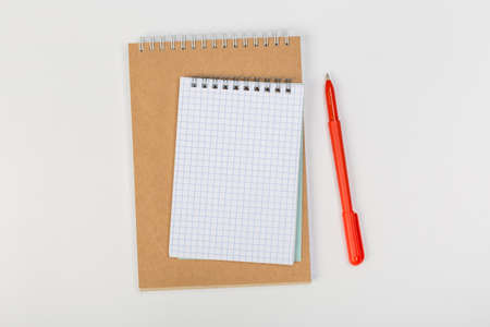 a stack of several spiral school notebooks lies on a white table with a pencil, office concept