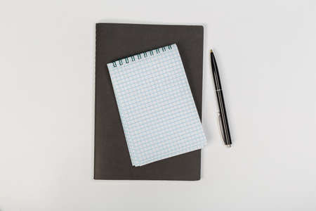 a stack of several spiral school notebooks lies on a white table with a pencil, office concept