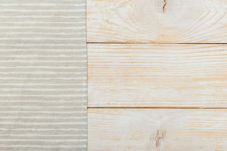 Top view on a white wooden table with a linen kitchen towel or textile napkin. a tablecloth on a light wood countertop. Copy space for text.の写真素材