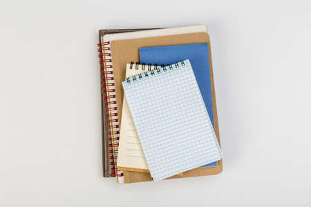 a stack of several spiral school notebooks lies on a white table with a pencil, office conceptの写真素材