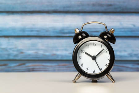 Black retro alarm clock with bells on a wooden table, daily routine concept. ten hours 10 minutesの写真素材