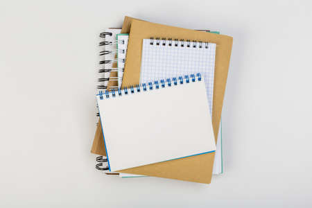 a stack of several spiral school notebooks lies on a white table with a pencil, office conceptの写真素材