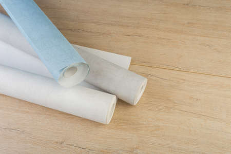 several rolls of multi-colored paper wallpaper on a wooden table