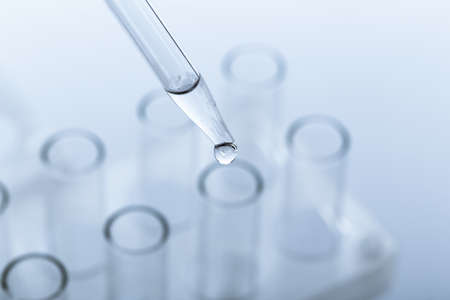 pipette with a drop and scientific laboratory test tubes in a research laboratory. study of a virus...