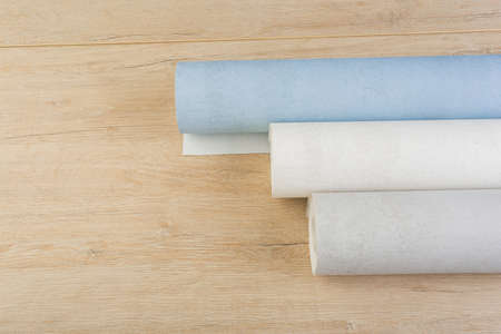 several rolls of multi-colored paper wallpaper on a wooden table