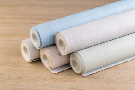 several rolls of multi-colored paper wallpaper on a wooden tableの写真素材