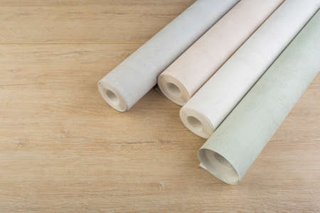 several rolls of multi-colored paper wallpaper on a wooden tableの写真素材